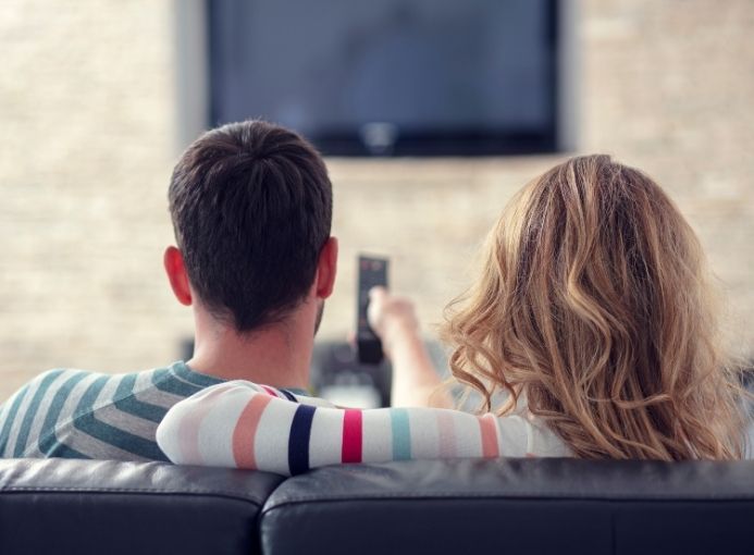 coppia sul divano guarda la tv
