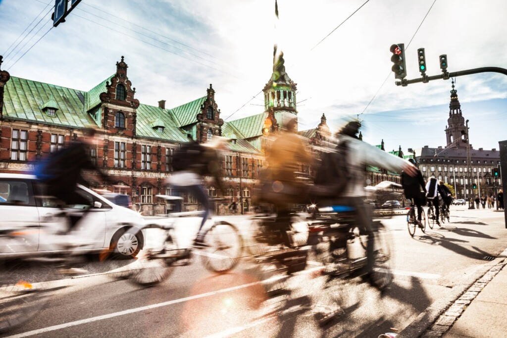 Ciclisti in movimento in una città europea con architettura storica, promozione della mobilità attiva e sostenibile