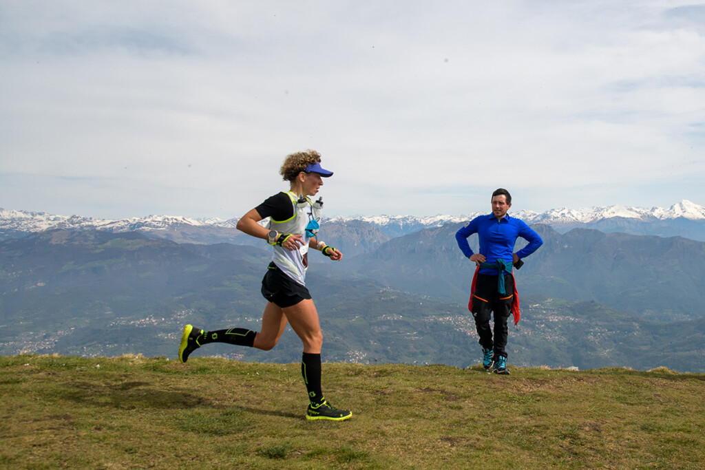 Daniela Rota in azione sul crinale del Monte Linzone durante il Linzone Trail 2024, con le Alpi innevate sullo sfondo