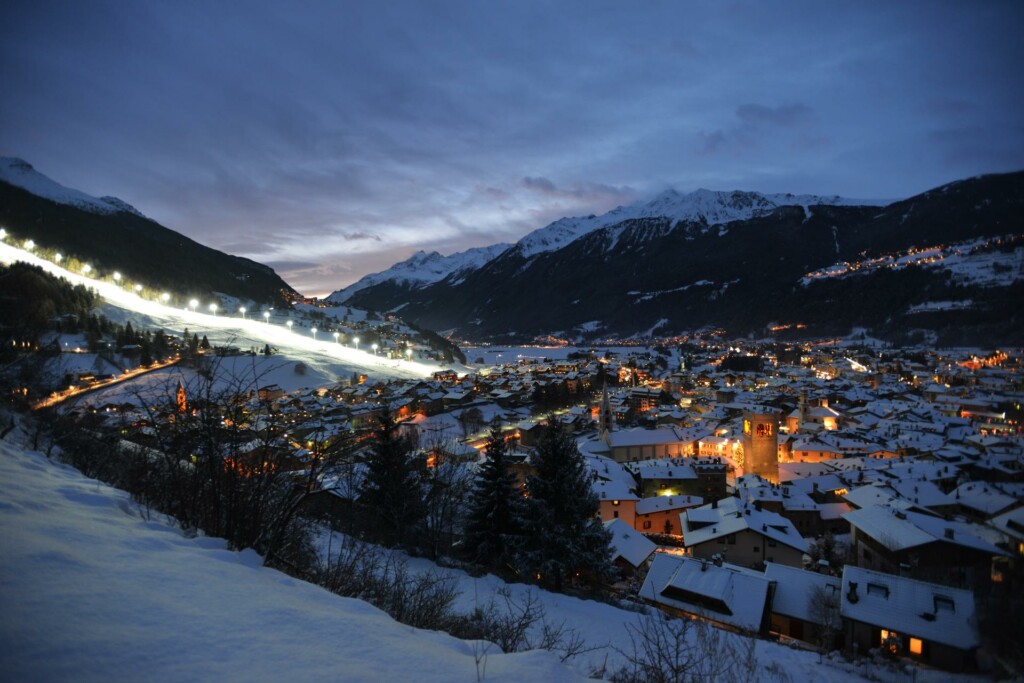 Veduta notturna di Bormio con la pista Stelvio illuminata, sede delle gare olimpiche di sci alpino e sci alpinismo di Milano Cortina 2026.