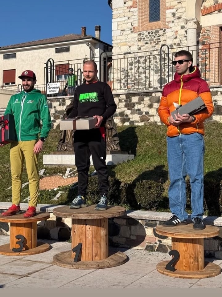 Podio maschile del percorso 14 km al Restena Trail 2025 di Arzignano, con i primi tre classificati premiati davanti alla chiesa di Restena.