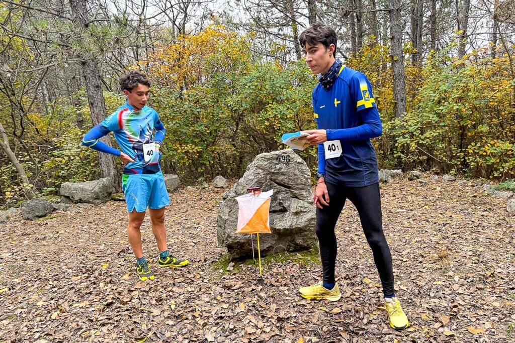 Due atleti, uno della Nazionale giovanile FISky e uno della rappresentativa FISO Veneto–Friuli Venezia Giulia, affrontano un punto di controllo durante la SkyRun in Orienteering 2025 nei boschi di Monfalcone.