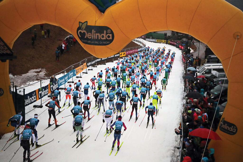 Partenza della 52ª Marcialonga di Fiemme e Fassa 2025, con il gruppo dei fondisti che lascia il via sotto il grande arco Melinda – photo Newspower.