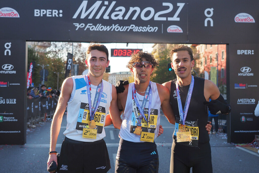 I primi tre classificati della 10 km della Milano21 2025 posano sotto il traguardo: Zahir Zohair vincitore, seguito da Mattia Campi e Rachid Es Skidri.