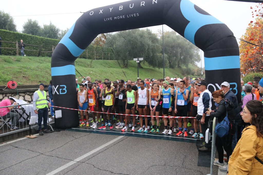 Runner schierati alla partenza della Padenghe Half Marathon 2025 sotto l’arco Oxyburn
