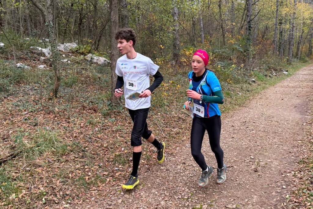 Coppia composta da atleta della rappresentativa FISO e atleta della Nazionale giovanile FISky impegnati nella SkyRun in Orienteering 2025 a Monfalcone, mentre corrono su un sentiero boschivo con carta di gara in mano.