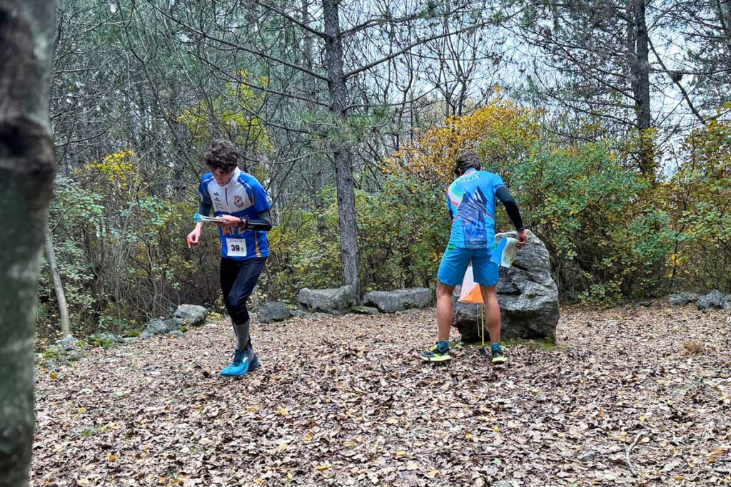 Due giovani atleti impegnati alla SkyRun in Orienteering 2025 a Monfalcone durante il passaggio al punto di controllo nel bosco.