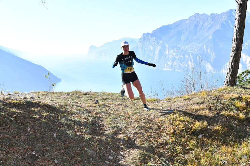 Runner in gara sul Garda Trentino durante un tratto panoramico con vista sul lago.