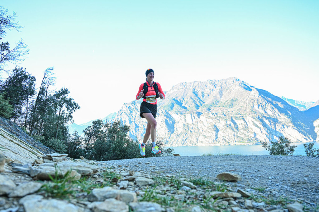 Atleta in gara lungo il percorso del Garda Trentino Xmas Trail con vista sul lago a Torbole