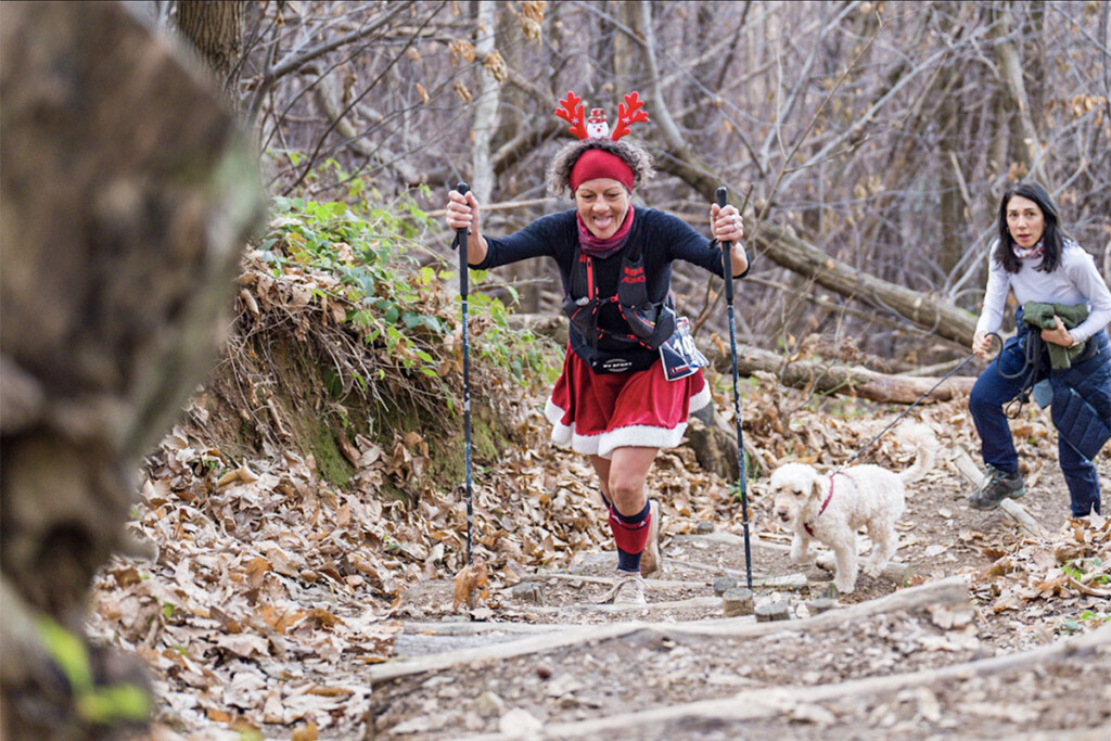 Cinzia Bertasa, atleta vincitrice del Monte Misma Xmas Trail 2025 in salita con bastoncini lungo un tratto boschivo del Monte Misma, durante la gara di Villa di Serio.
