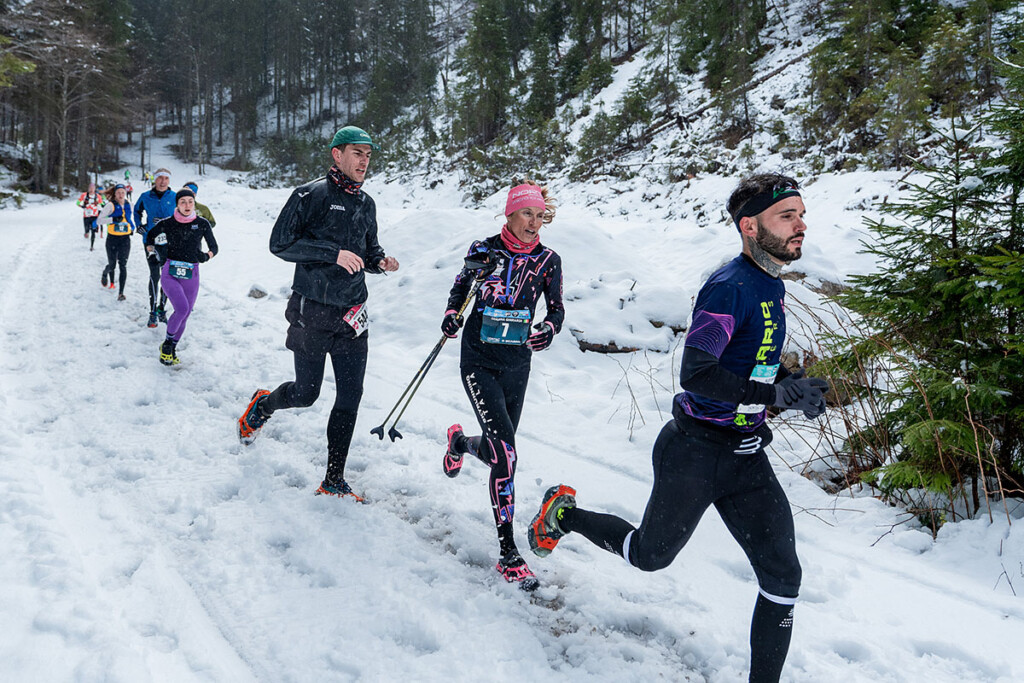 Atleti in gara alla Tarvisio Winter Trail sul Monte Mangart, in corsa su fondo nevoso tra i boschi.