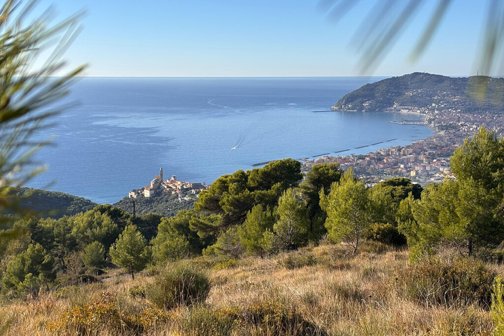 Vista del borgo di Cervo e del Golfo Dianese dal Parco del Ciapà, con mare e macchia mediterranea.